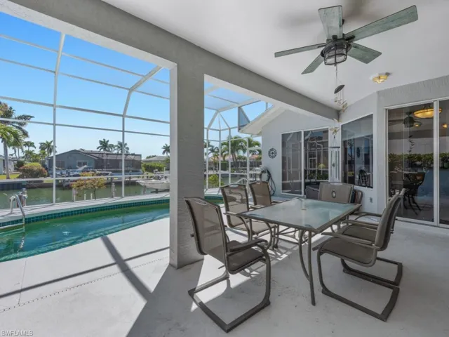 View of patio with an outdoor pool, a water view, glass enclosure, and ceiling fan