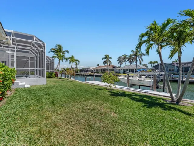 View of yard featuring boat lift, a water view, glass enclosure, and a boat dock