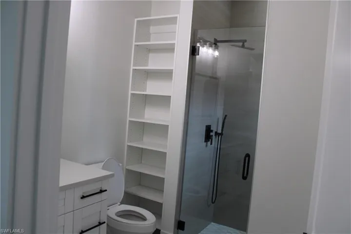 Contemporary bathroom featuring a frameless glass shower enclosure, a rainfall showerhead, and matte black fixtures