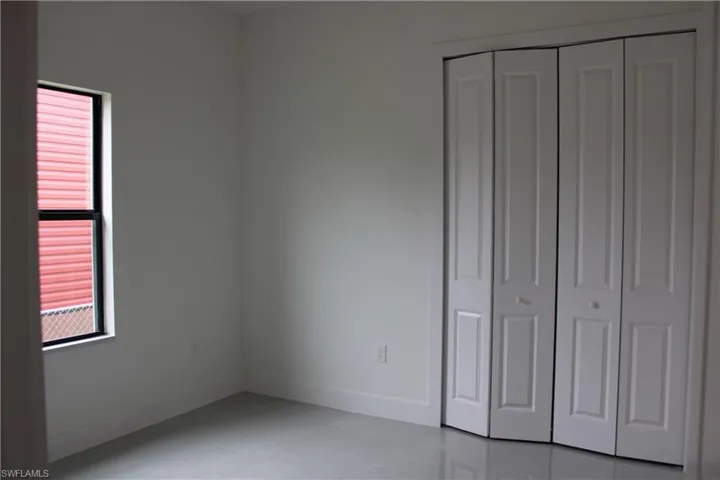Neutral interior featuring light gray walls and a single window with a dark frame