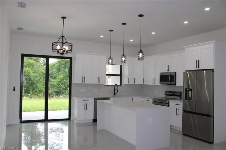 Contemporary kitchen featuring white shaker cabinetry, stainless steel appliances, and a central island with a quartz countertop