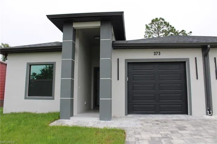 Modern exterior featuring a prominent covered entryway with stacked stone-look pillars