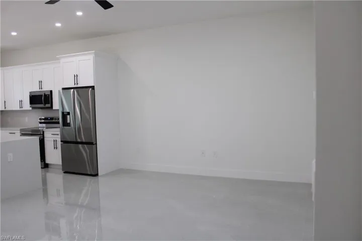 Open-concept interior featuring bright white walls, light-toned flooring, and recessed lighting