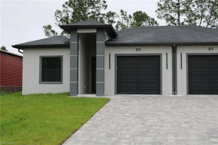 Duplex exterior featuring light stucco siding with dark gray trim accents and a dark shingle roof