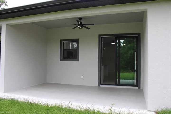 Covered patio featuring a ceiling fan, a fixed-pane window with dark trim, and sliding glass doors with dark frames