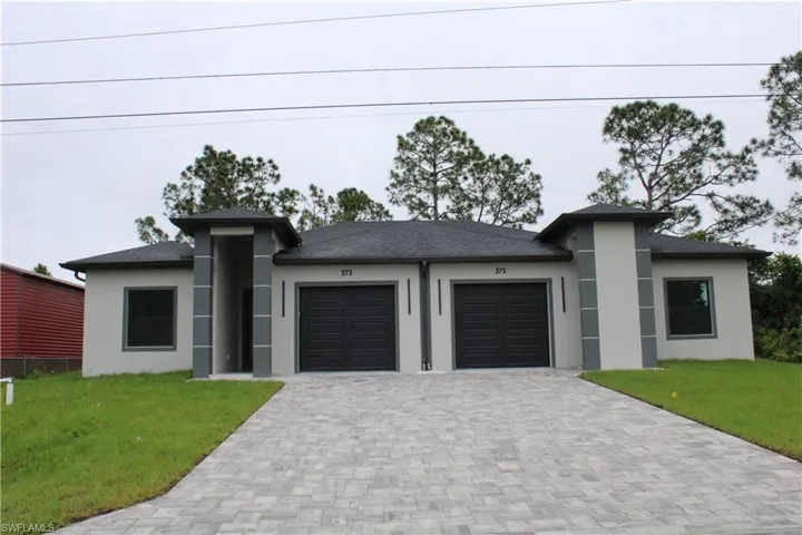 Contemporary duplex with light stucco exterior, dark asphalt shingle roof, and paver driveways