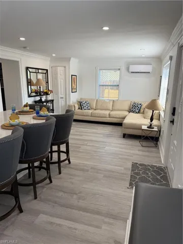 Dining area with crown molding, a wall unit AC, and light hardwood / wood-style flooring
