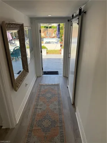 Bedroom featuring a barn door, ensuite bath, light wood-type flooring, and a closet
