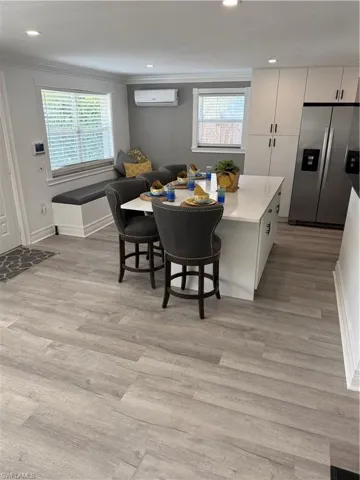 Dining area featuring ornamental molding, a wall mounted AC, and light wood-type flooring