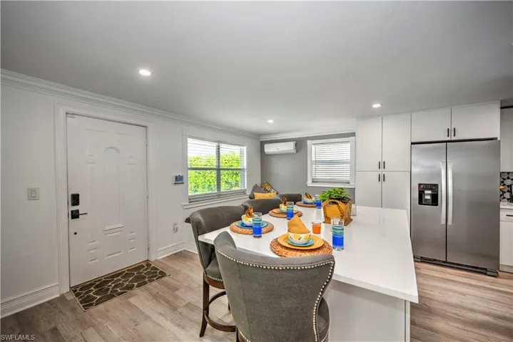 Kitchen with white cabinetry, light stone counters, tasteful backsplash, stainless steel appliances, and light hardwood / wood-style floors