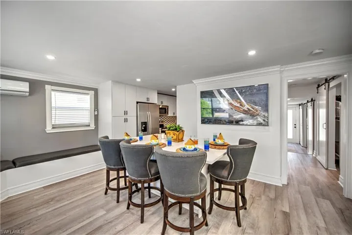 Living room featuring crown molding, a healthy amount of sunlight, light hardwood / wood-style flooring, and an AC wall unit