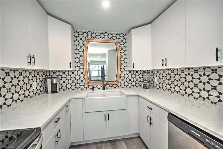 Kitchen with white cabinetry, sink, decorative backsplash, and stainless steel appliances