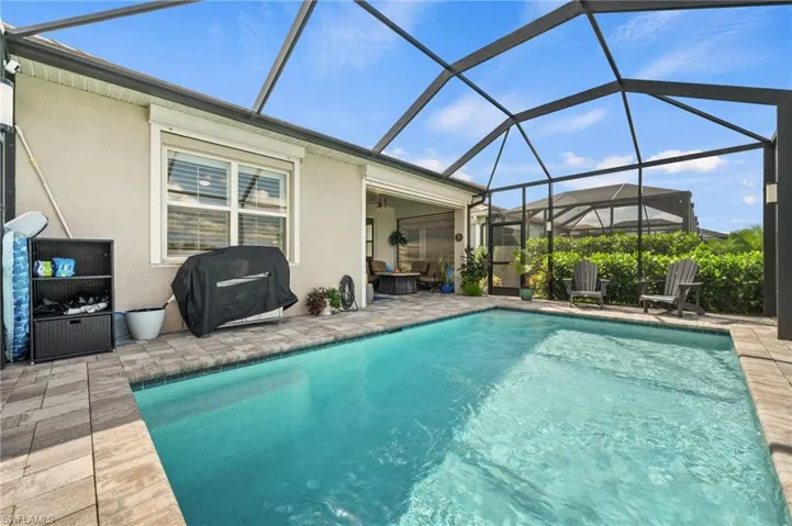 View of pool featuring a patio area, glass enclosure, area for grilling, and ceiling fan