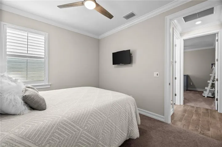 Bedroom with crown molding, hardwood / wood-style flooring, and ceiling fan