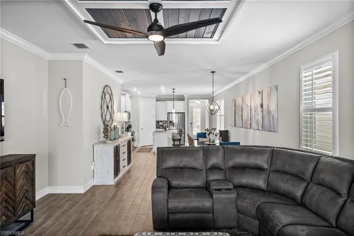 Living room with ornamental molding, ceiling fan with notable chandelier, and dark hardwood / wood-style flooring