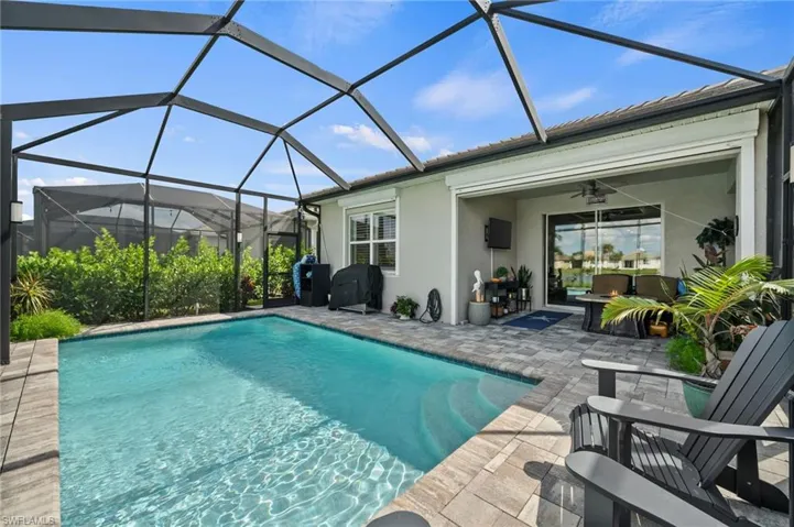 View of pool with a lanai, ceiling fan, a patio, and grilling area