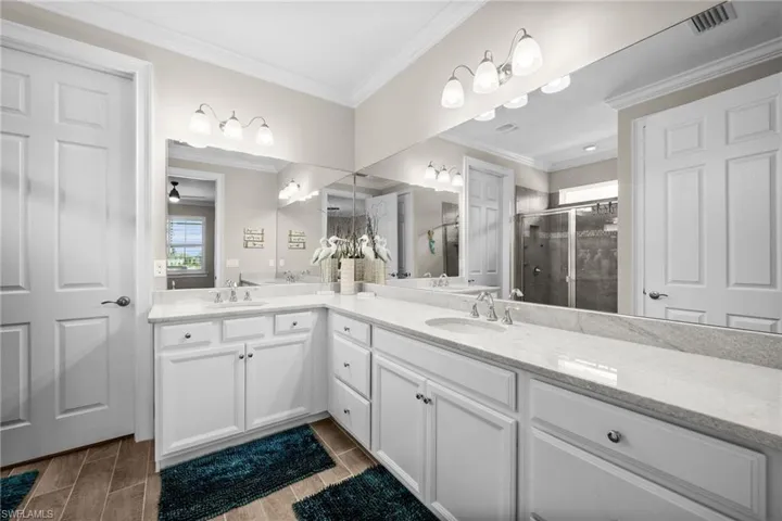 Bathroom with ornamental molding, a shower with shower door, vanity, and hardwood / wood-style flooring
