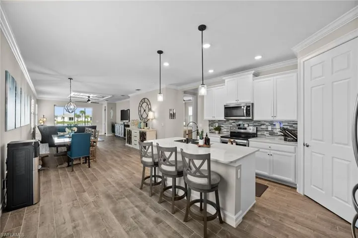 Kitchen with appliances with stainless steel finishes, white cabinetry, a center island with sink, and light hardwood / wood-style floors