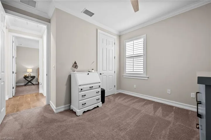 Carpeted bedroom with crown molding and ceiling fan