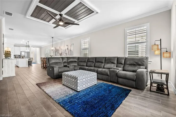 Living room with wood-type flooring, crown molding, and a healthy amount of sunlight
