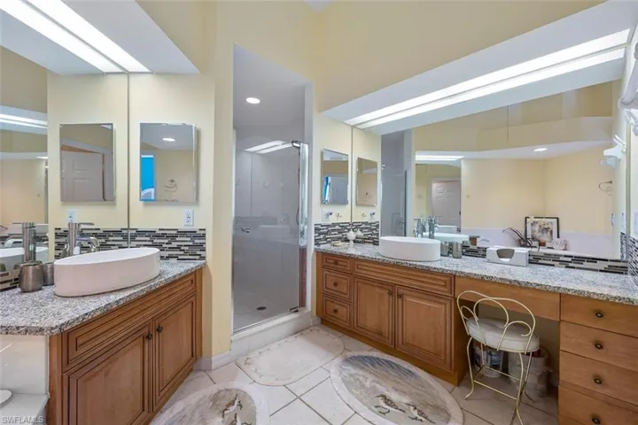 Full bath featuring tasteful backsplash, two vanities, and a sink