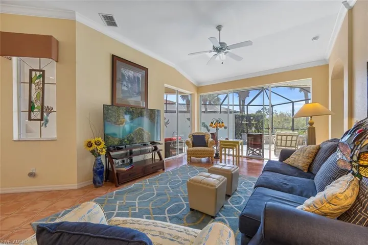 Tiled living area with crown molding, visible vents, a sunroom, ceiling fan, and baseboards