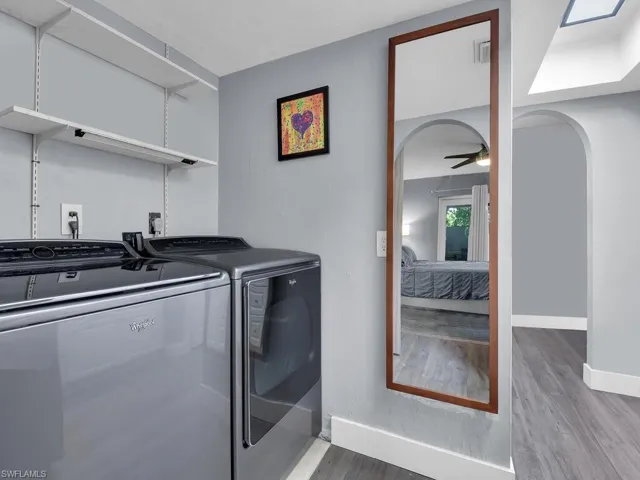 Laundry area featuring separate washer and dryer, wood finished floors, arched walkways, and ceiling fan
