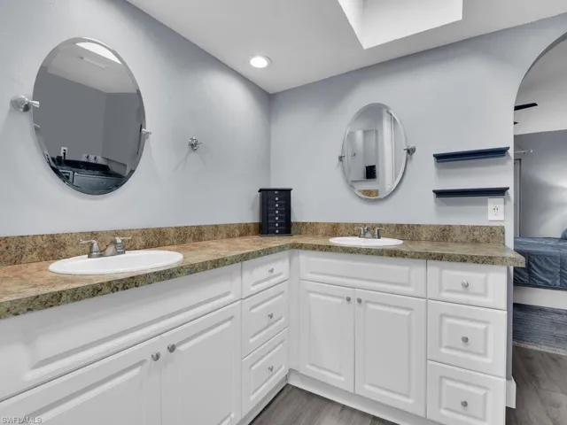 Ensuite bathroom with double vanity, wood finished floors, and recessed lighting