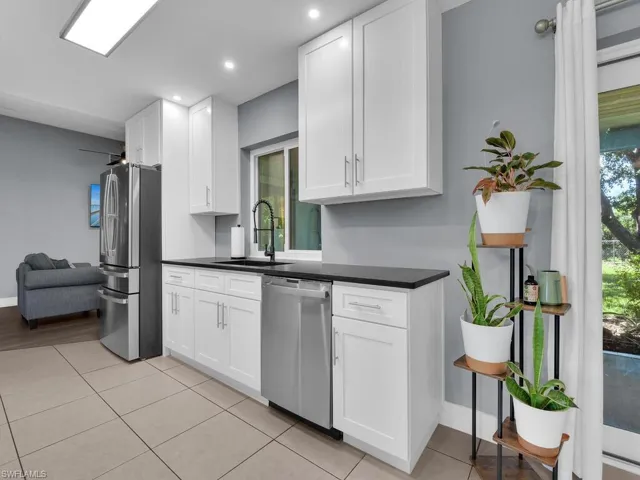 Kitchen featuring appliances with stainless steel finishes, dark countertops, light tile patterned flooring, white cabinetry, and recessed lighting