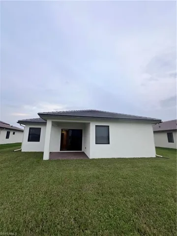 Back of house with a patio area and a lawn