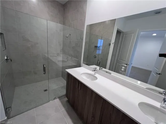 Bathroom with vanity, tile patterned flooring, and an enclosed shower