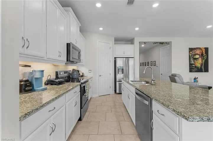 Kitchen featuring white cabinetry, sink, a kitchen island with sink, and stainless steel appliances