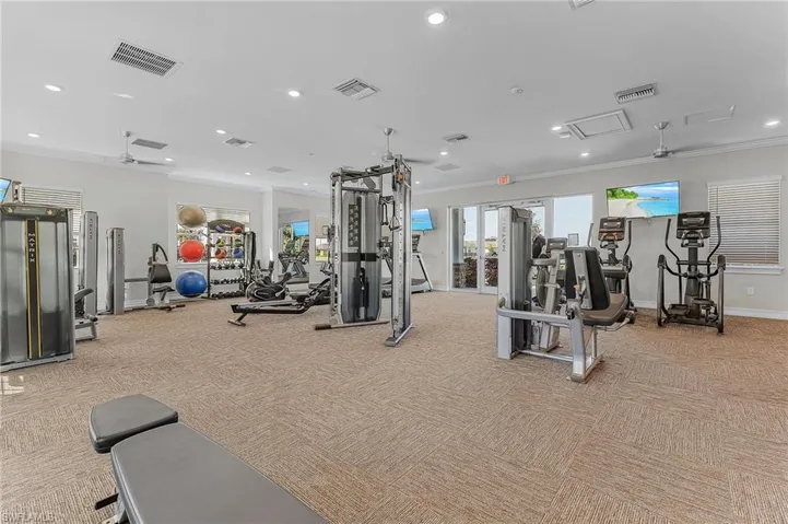 Gym featuring ornamental molding, light colored carpet, and ceiling fan