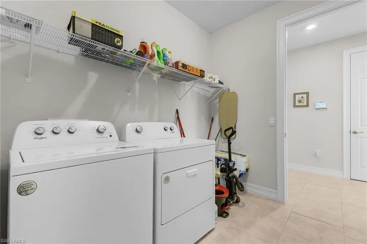 Laundry room with light tile patterned floors and washing machine and dryer