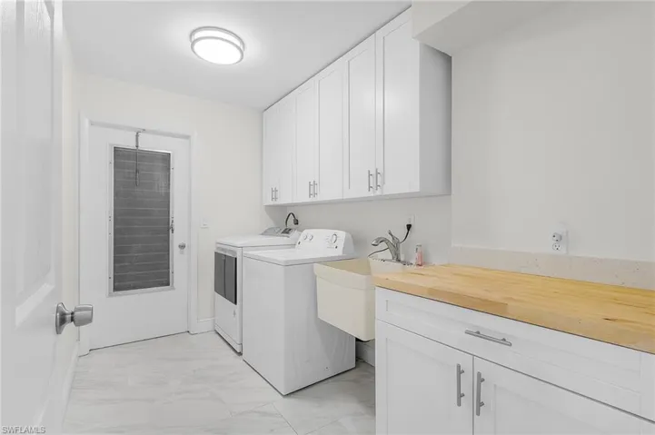 Clothes washing area featuring marble finish floor, separate washer and dryer, a sink, and cabinet space