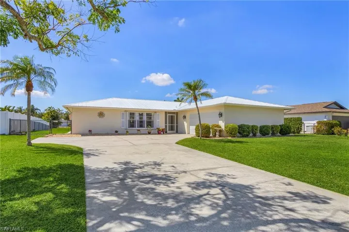 Ranch-style house with concrete driveway, a front lawn, an attached garage, and fence