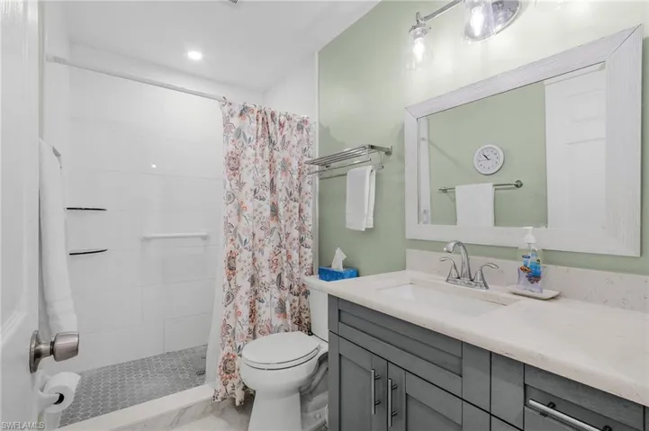 Bathroom with tiled shower, vanity, and toilet