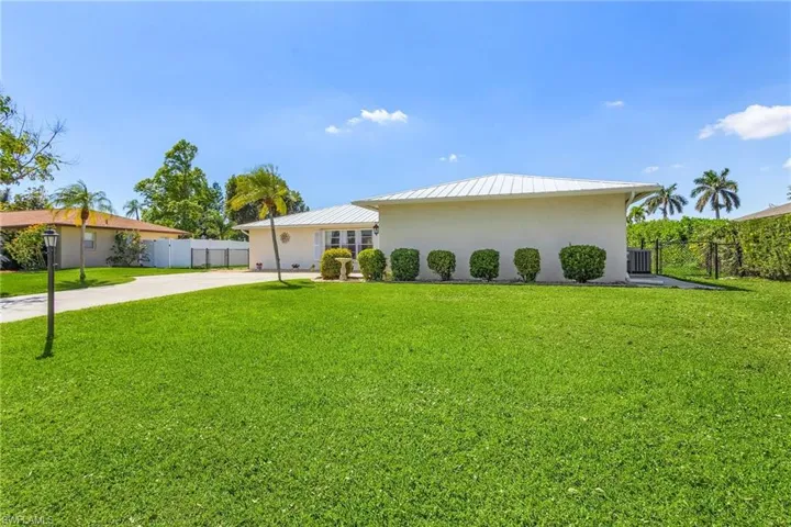 View of front of home with metal roof, fence, a front lawn, and stucco siding