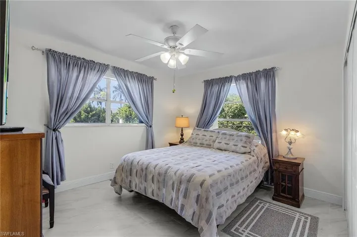 Bedroom featuring marble finish floor, ceiling fan, and baseboards