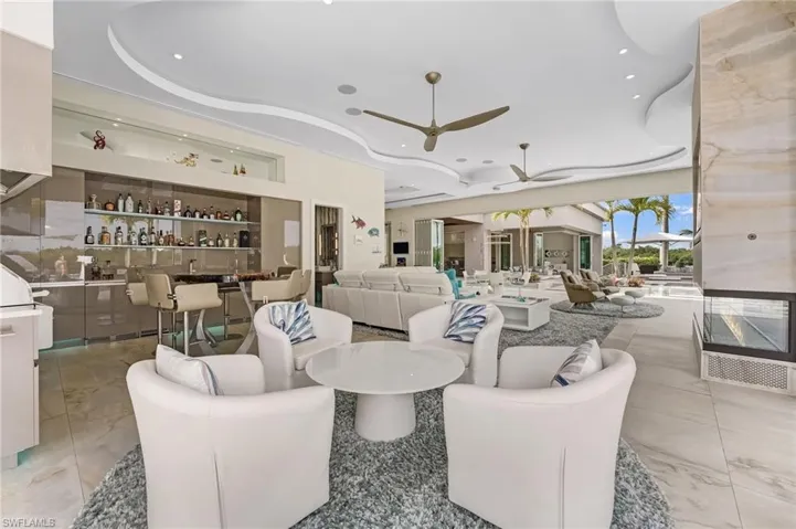 The expansive bar area is perfectly appointed for entertaining, featuring an icemaker and additional refrigeration, seamlessly integrated within the indoor kitchen to enhance both functionality and style.