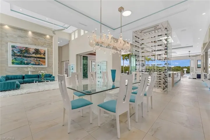This bespoke residence offers an open, flowing design where the formal living room transitions seamlessly into the dining area, creating an elegant sense of continuity throughout the main living spaces. A striking temperature-controlled wine cellar, enclosed in seamless glass and accommodating over 250 bottles, serves as a sophisticated architectural divider, beautifully separating the living and dining areas from the expansive kitchen.