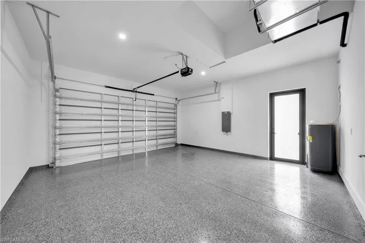 Interior garage space featuring a speckled epoxy floor, recessed lighting, and a frosted glass door