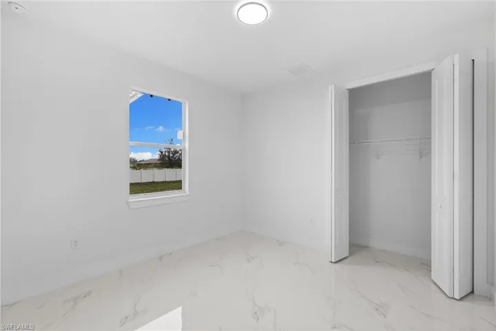 Unfurnished bedroom with baseboards, marble finish floors, and a closet