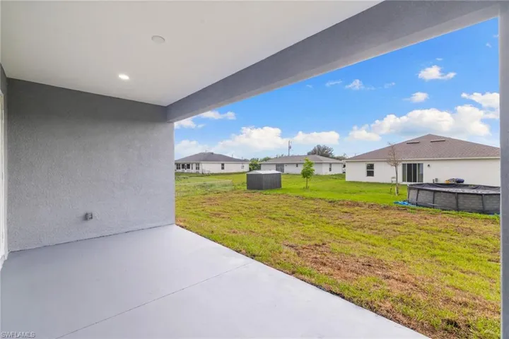 View of green lawn with a patio area and a residential view