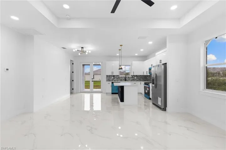 Kitchen with appliances with stainless steel finishes, plenty of natural light, a kitchen island, baseboards, and recessed lighting
