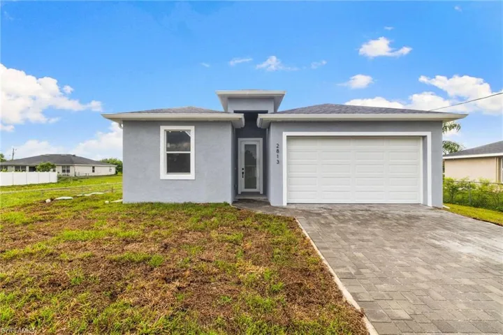 View of front of home featuring decorative driveway, stucco siding, and a garage