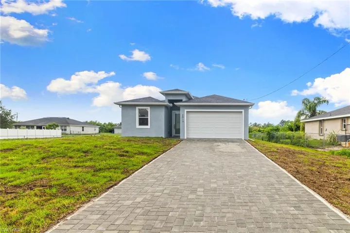 View of front of home featuring stucco siding, an attached garage, and decorative driveway