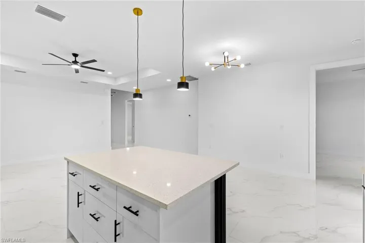 Kitchen featuring light marble finish floors, recessed lighting, a center island, baseboards, and decorative light fixtures