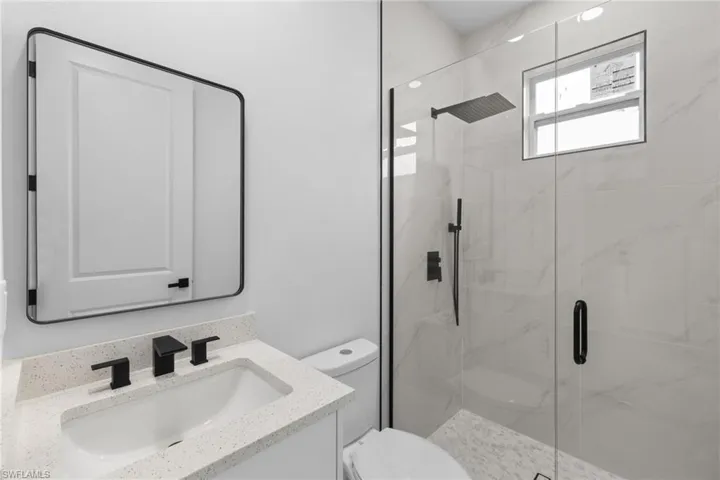 Bathroom featuring toilet, a marble finish shower, and vanity