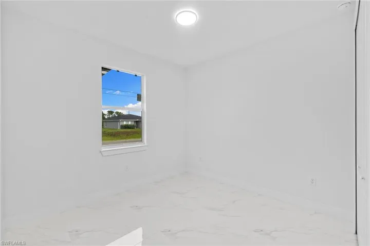 Empty room featuring marble look tile flooring and baseboards